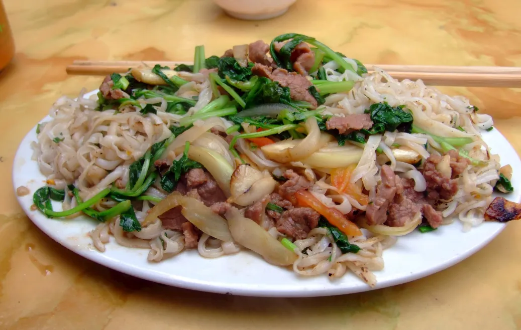 Vietnamese pho xao noodles being stir-fried in a wok