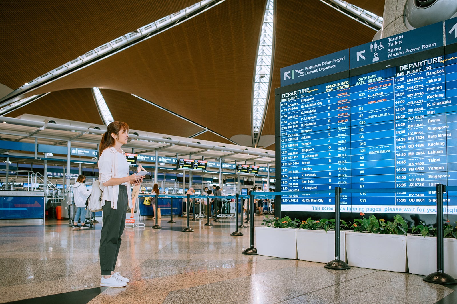 Passanger-looking-at-flight-schedule-time-on-information-board-at-airport_KSChong