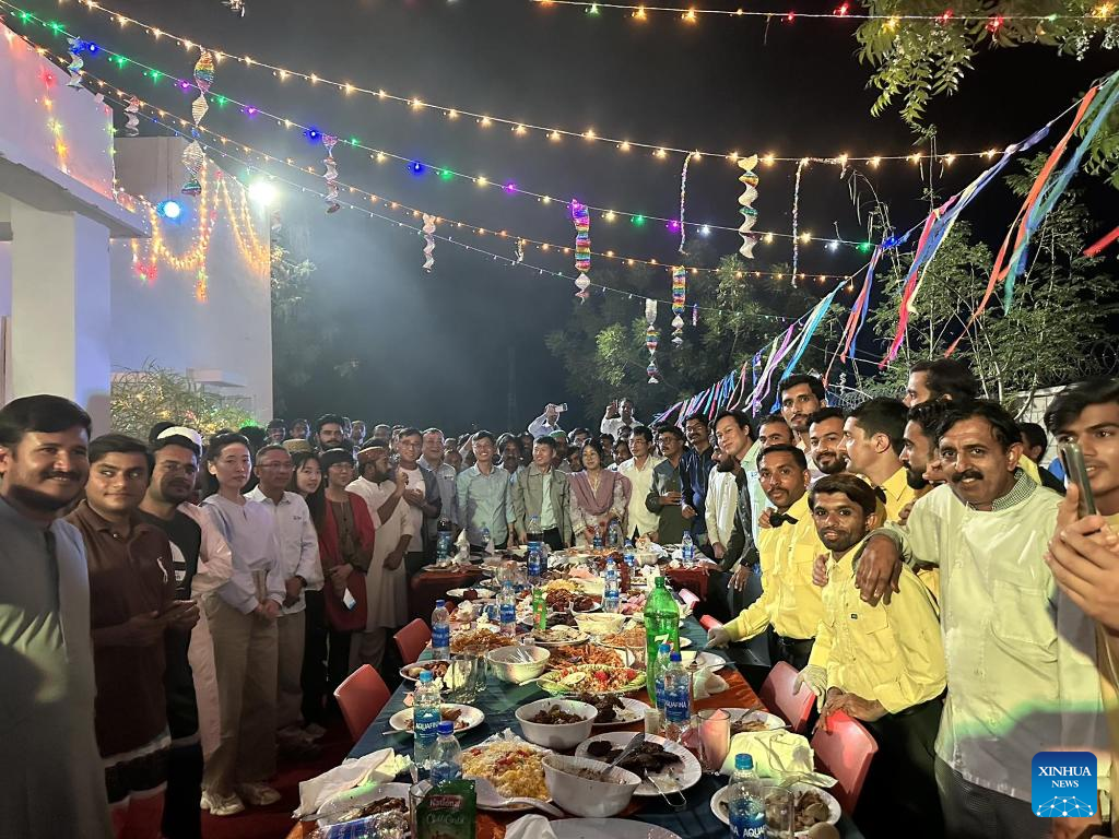 This photo taken on April 22, 2023 shows Chinese and Pakistani staff members of the Thar Coal Block-II Coal Electricity Integration project posing for a group photo during a dinner celebrating Eid al-Fitr in the Thar Desert in Pakistan's south Sindh province. (Str/Xinhua)