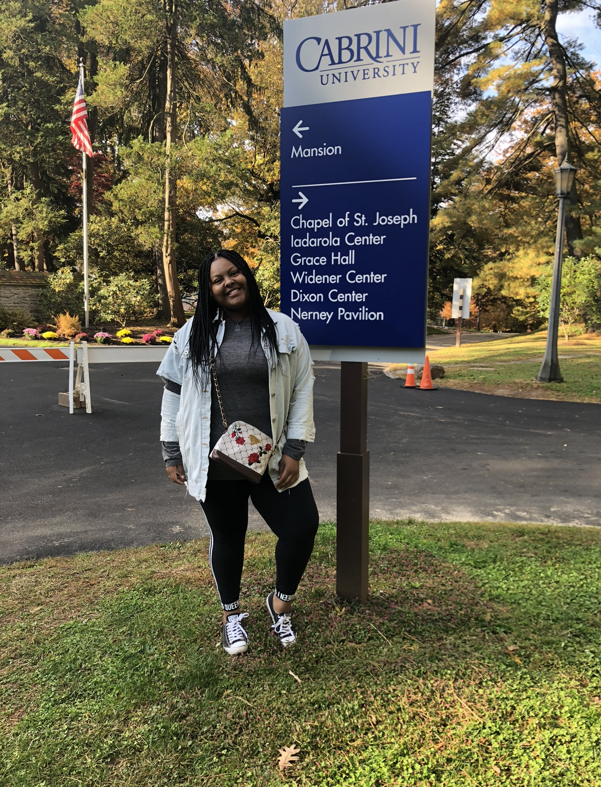 Lashay Smith standing next to a Cabrini sign on campus.