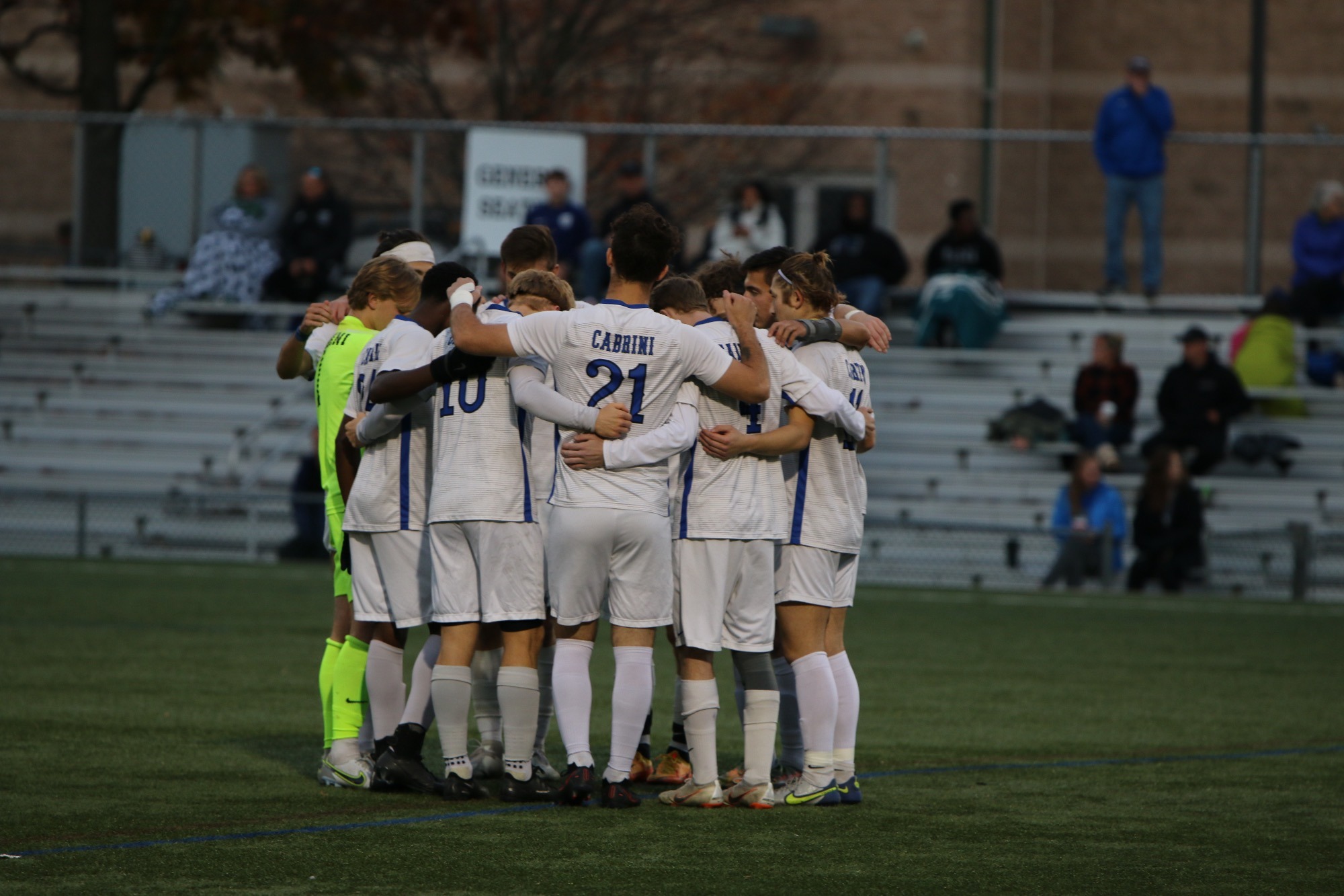 Photo of Cabrini's Mens soccer team huddling up during a game.