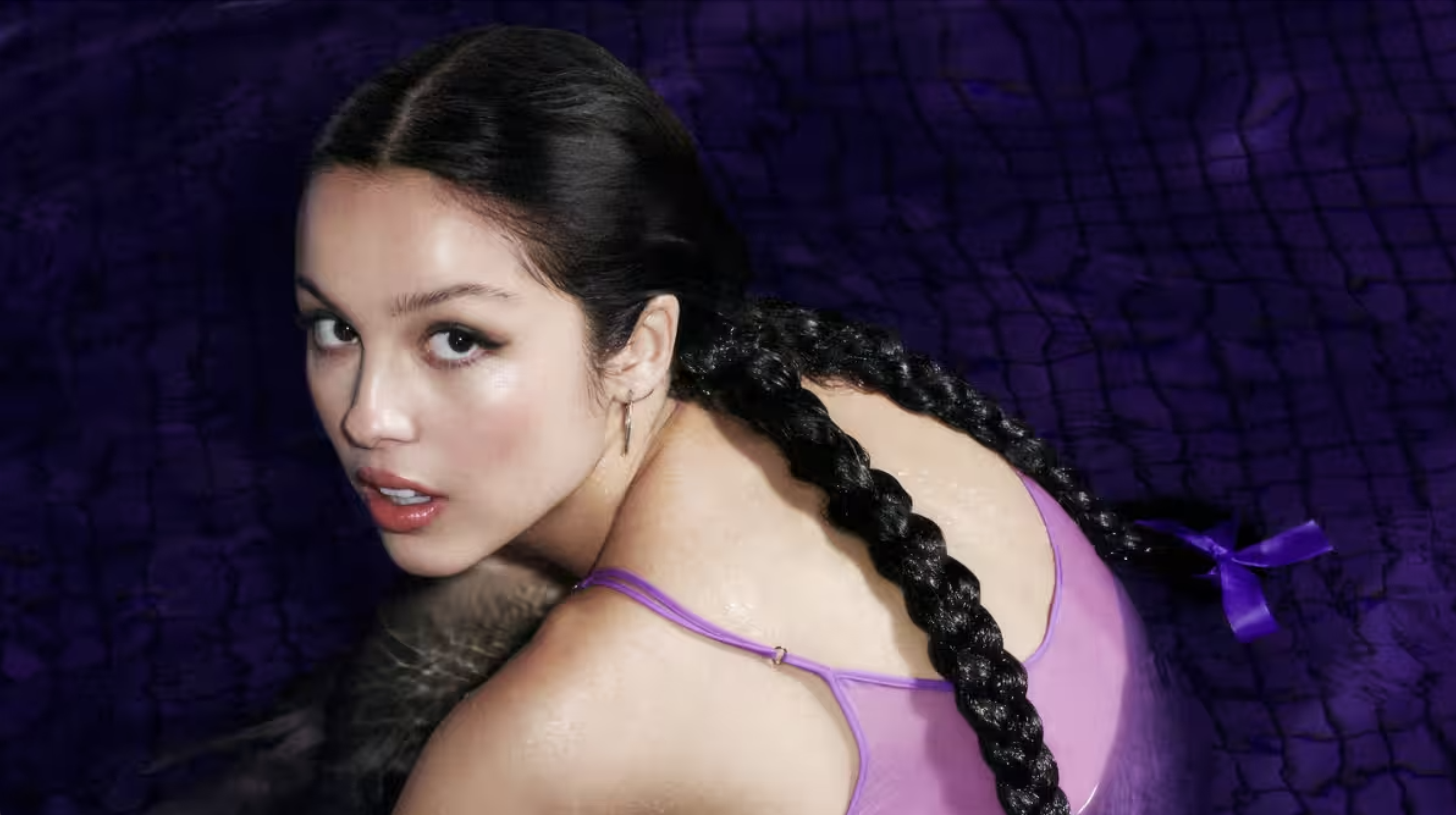 Olivia Rodrigo sits in purple water for her album's photoshoot.
