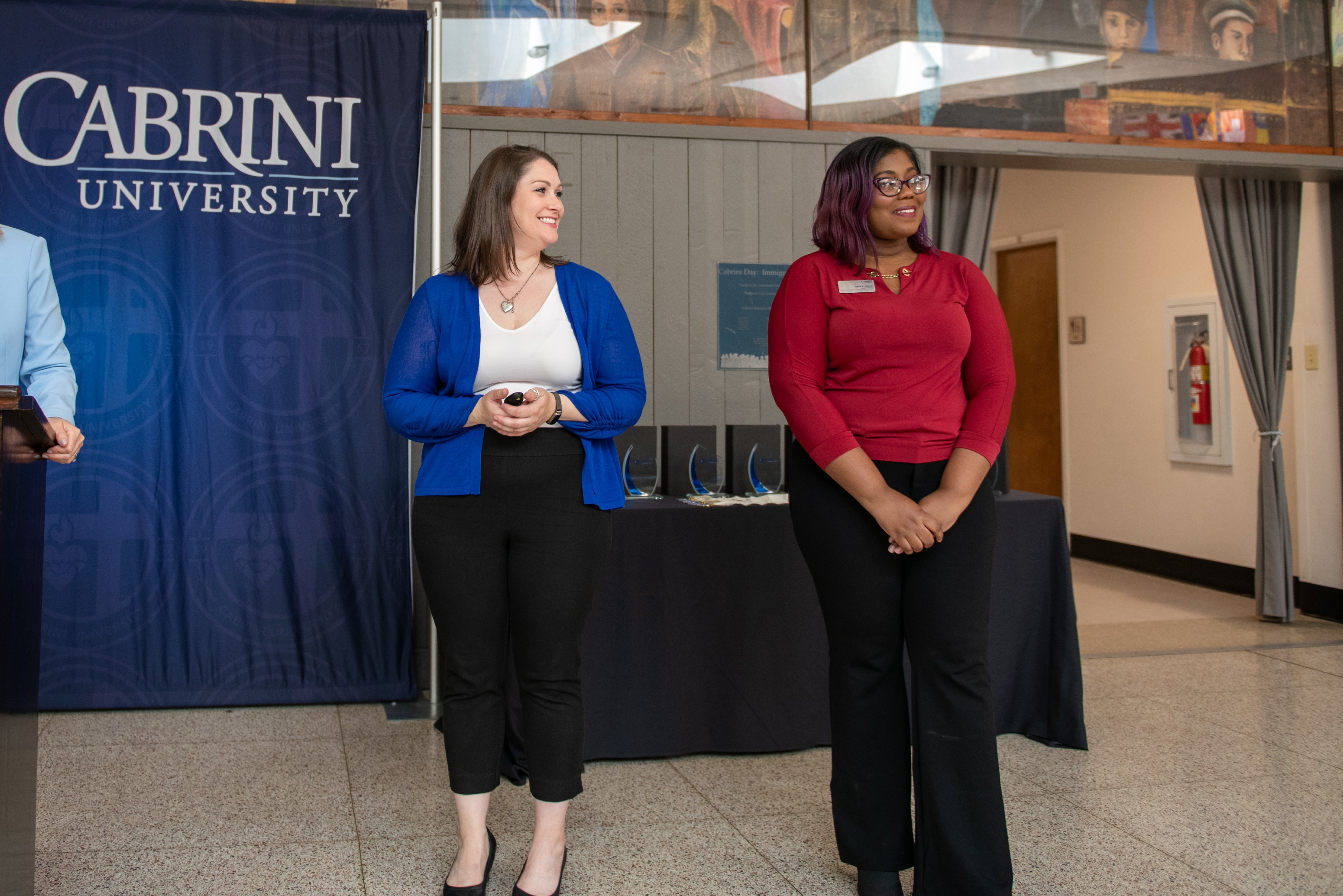 The SEal Director and assistant director stand in front of an audience presenting at Cabrini.