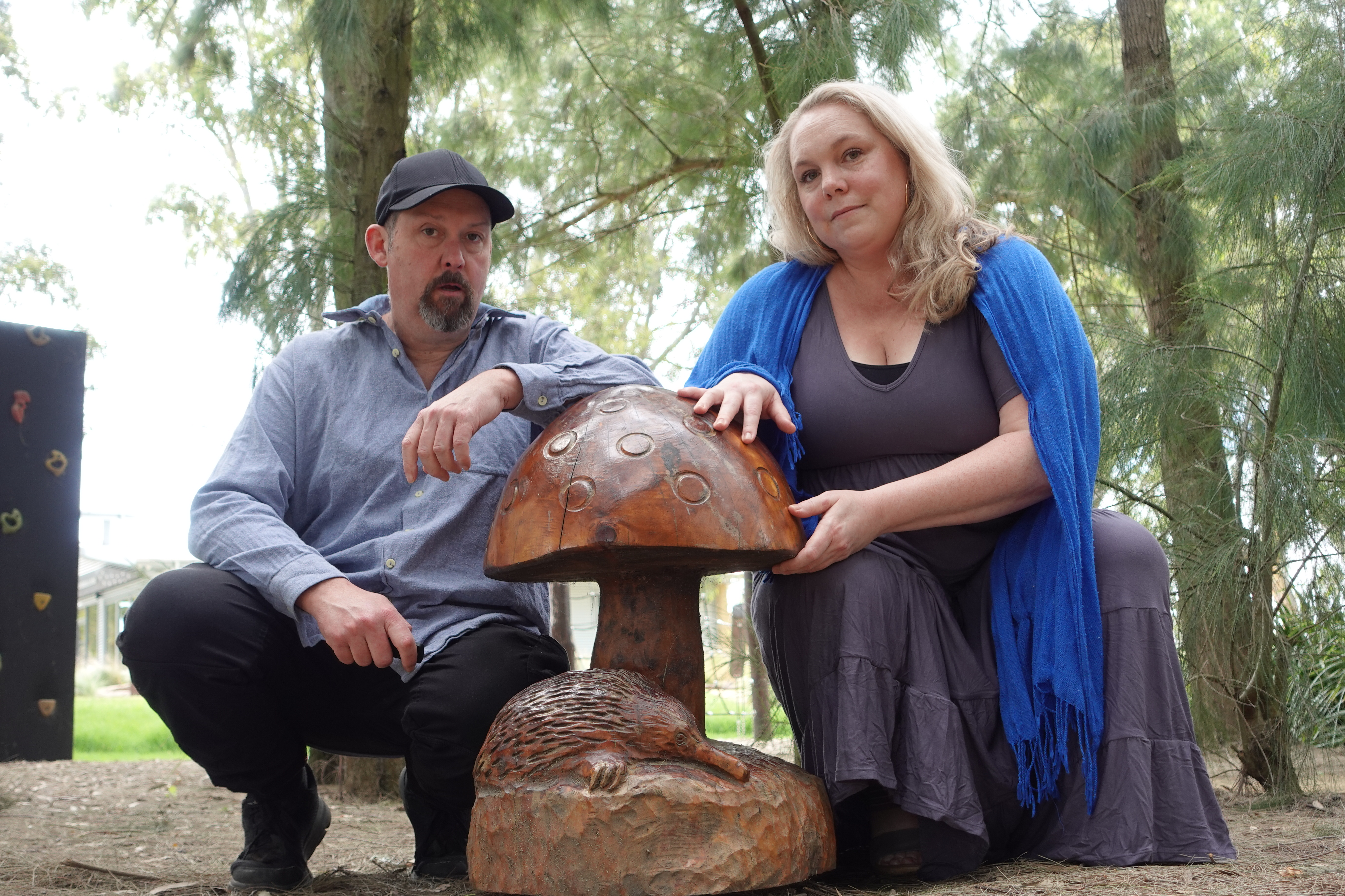 About 3 a man and woman posing with a statue