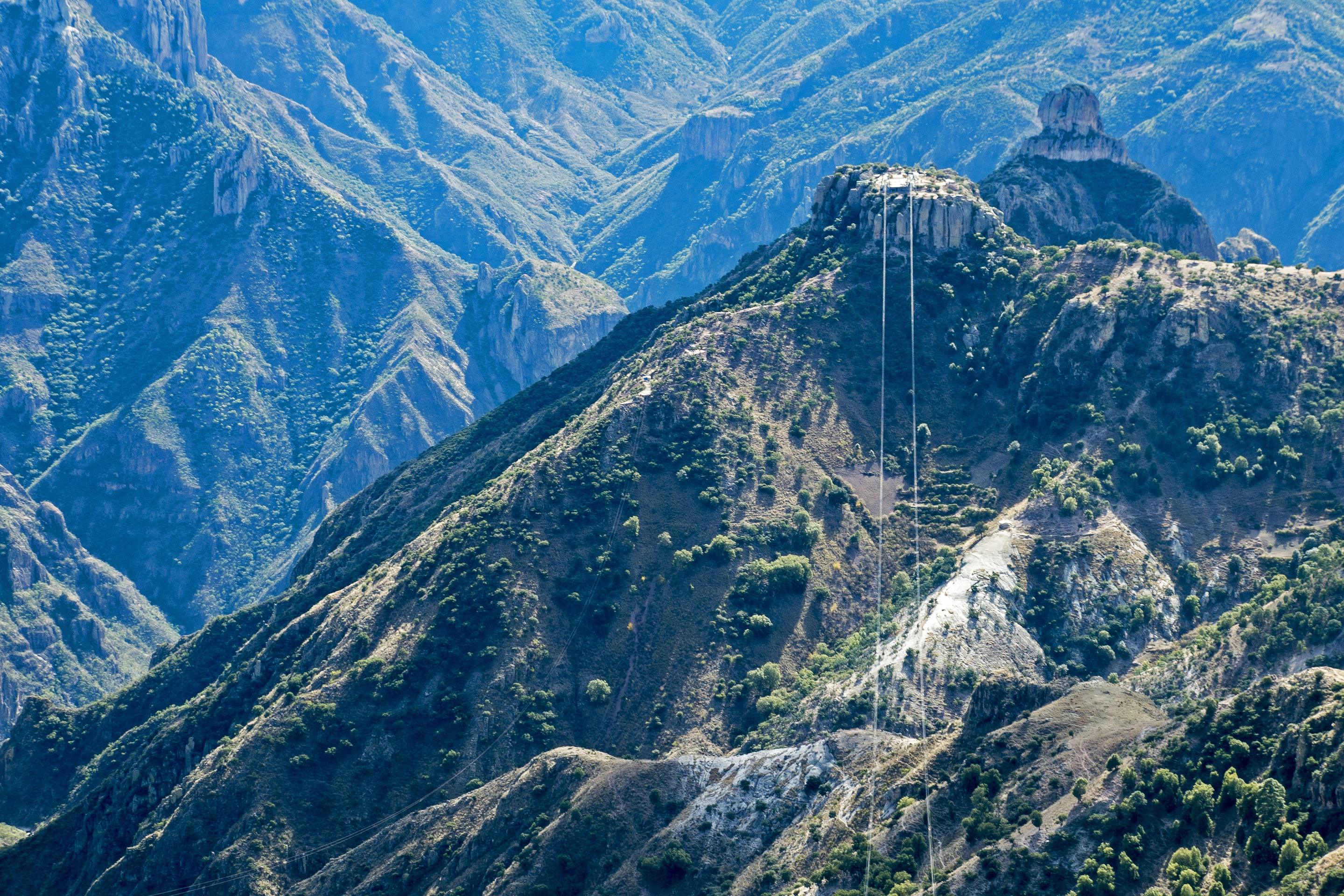 The cable-car wires of Divisadero running out over a forested rock peak above the canyon