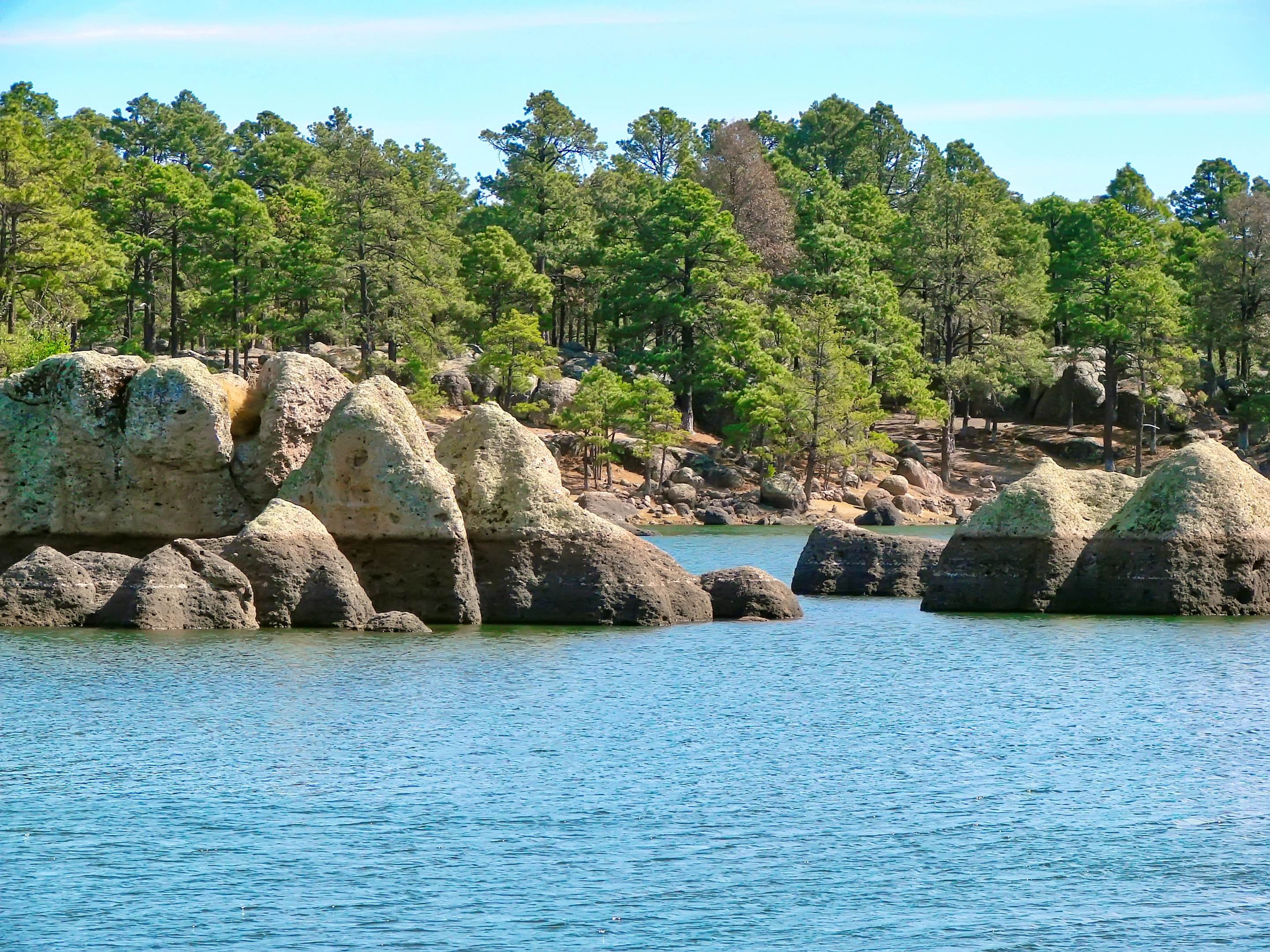 Lake Arareco near Creel, with rounded boulders at the shore and a pine forest behind