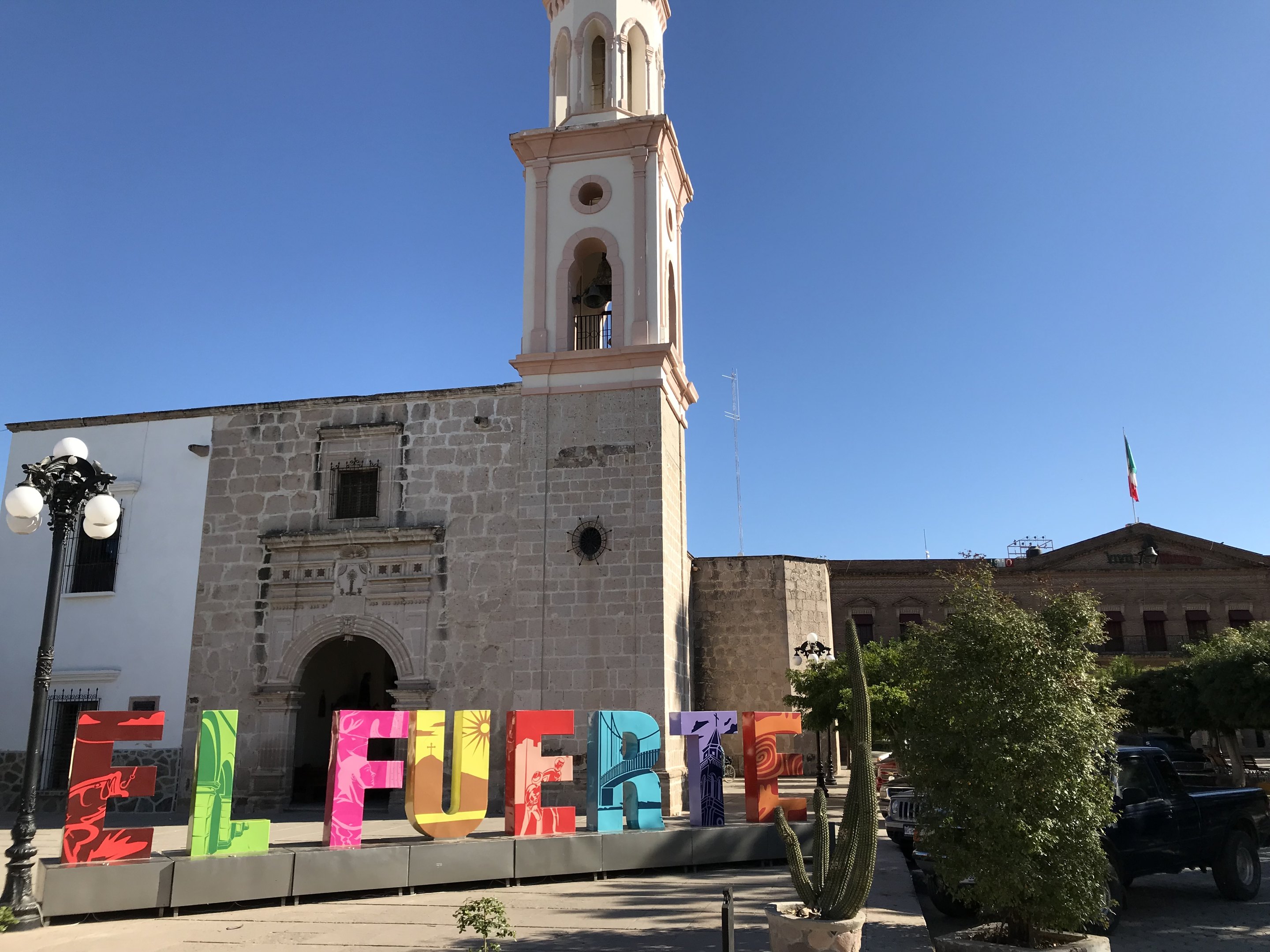 The church of El Fuerte and its bell tower, with large colorful letters spelling the town's name in front