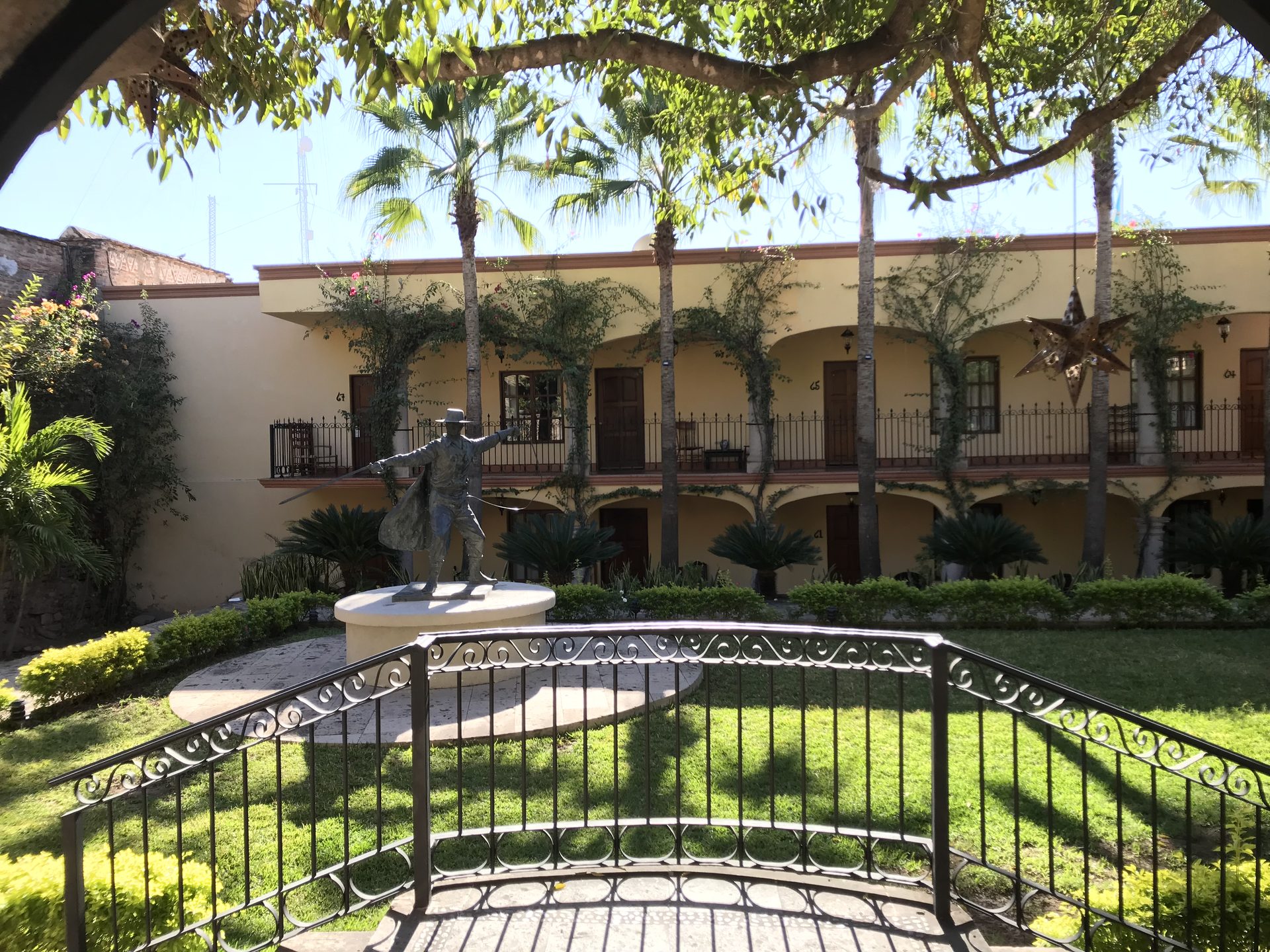 A courtyard with palms, a statue and arched colonial galleries in El Fuerte