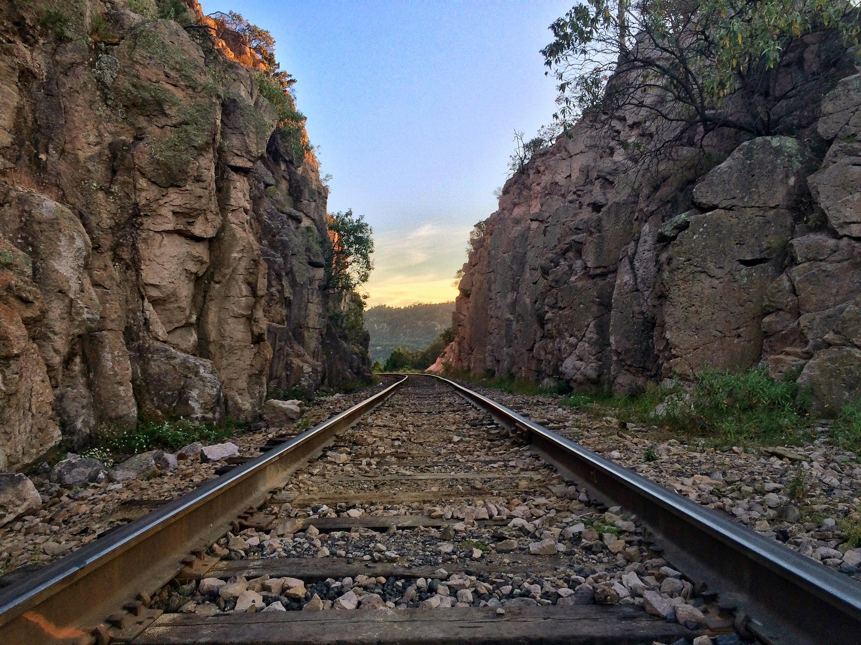 The track running away between two rock walls of a cutting, sunset light at the far end