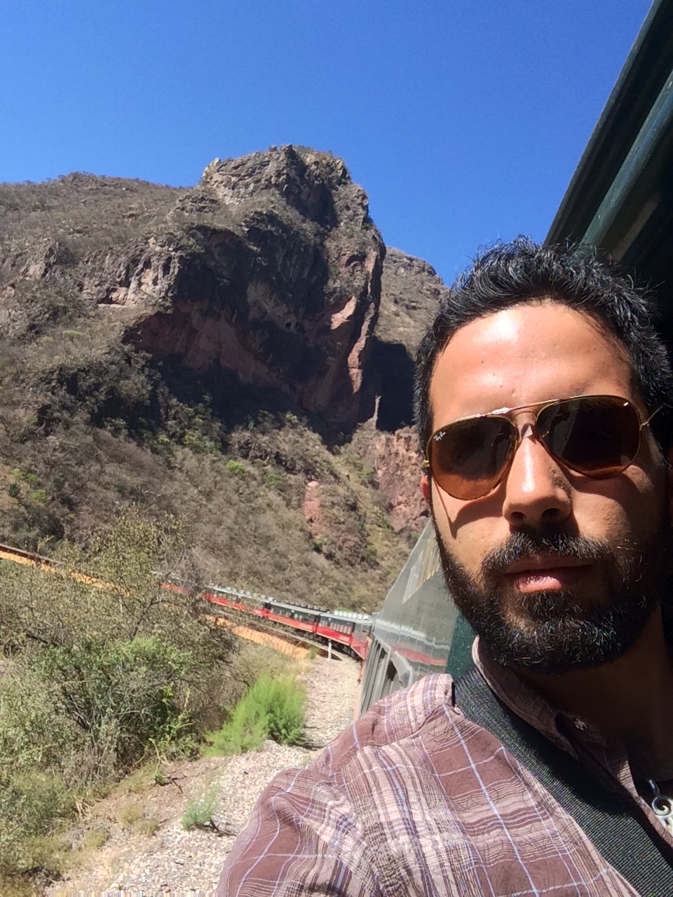 Selfie on El Chepe, with the train curving past a rocky canyon wall