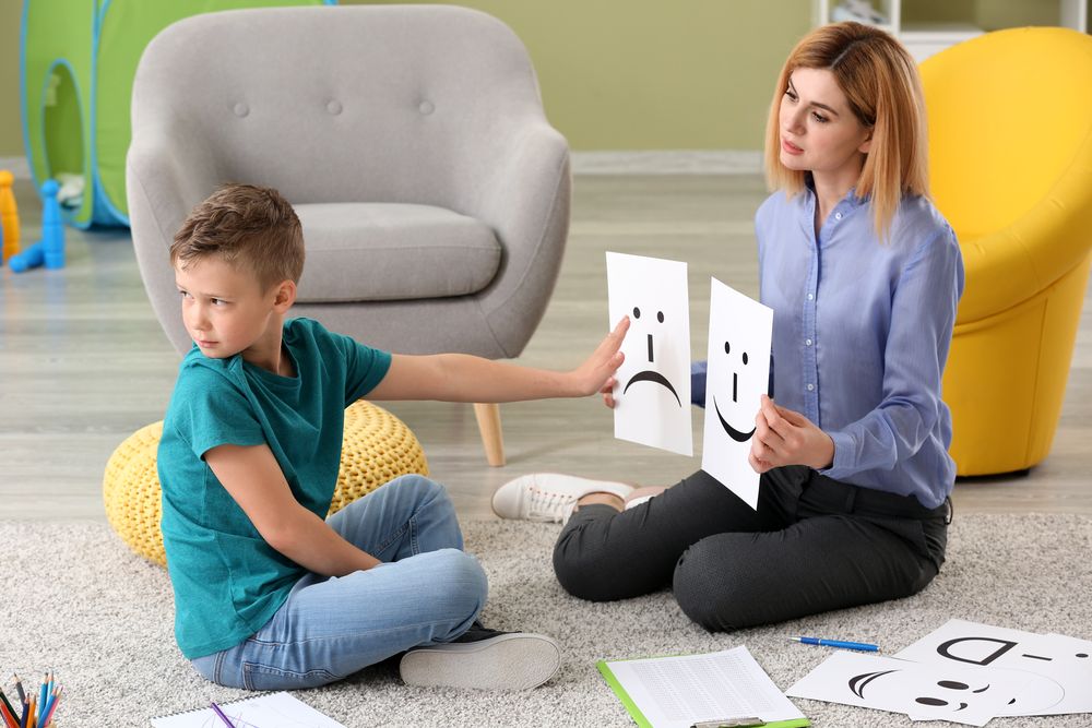 Female psychologist working with boy suffering from autistic disorder