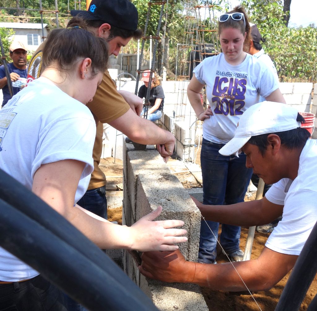 Cabrini students Mackenzie Harris, Nick Cipollone and Abby Pressimone learn from a Guatemalan worker how to lay cinder blocks for a future home. 