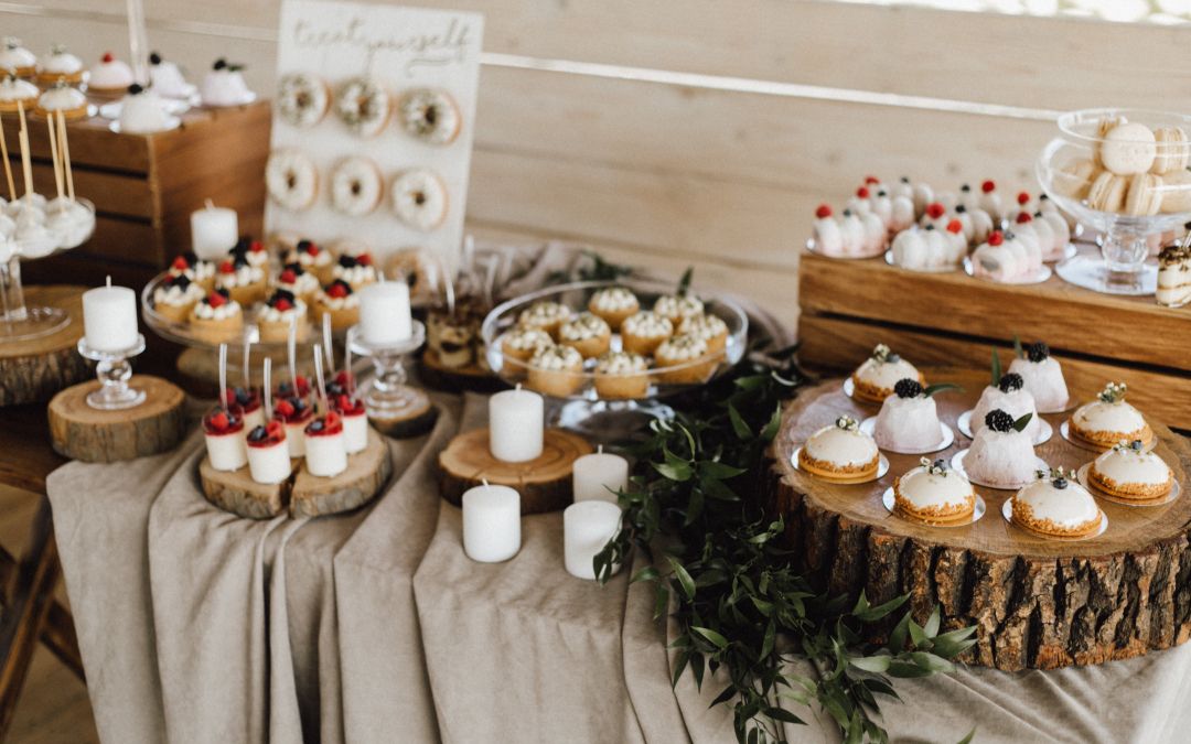 An array of assorted desserts displayed on rustic wooden stands at a catering event.