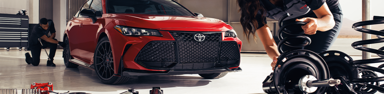 Top Ten FAQs For New Car Buyers in East Petersburg, PA | Mechanic grabbing some car parts while a red 2023 Toyota Camry is parked behind her