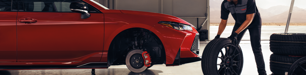 Top Ten FAQs For New Car Buyers in East Petersburg, PA | Mechanic changing out the car tires with new ones for a red 2023 Toyota Camry