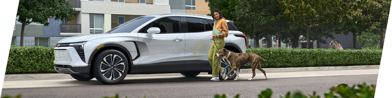Car Technology Trends at CMA Chevrolet of Martinsburg in Martinsburg, WV | 2024 Chevrolet Blazer EV parked curbside while a woman is walking her dog beside it