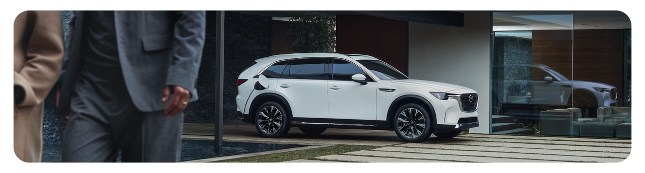 How to prepare your home for your new Electric Vehicle at Lancaster Mazda in Lancaster, PA | White 2025 Mazda CX-90 charging in at home while couple walks into home