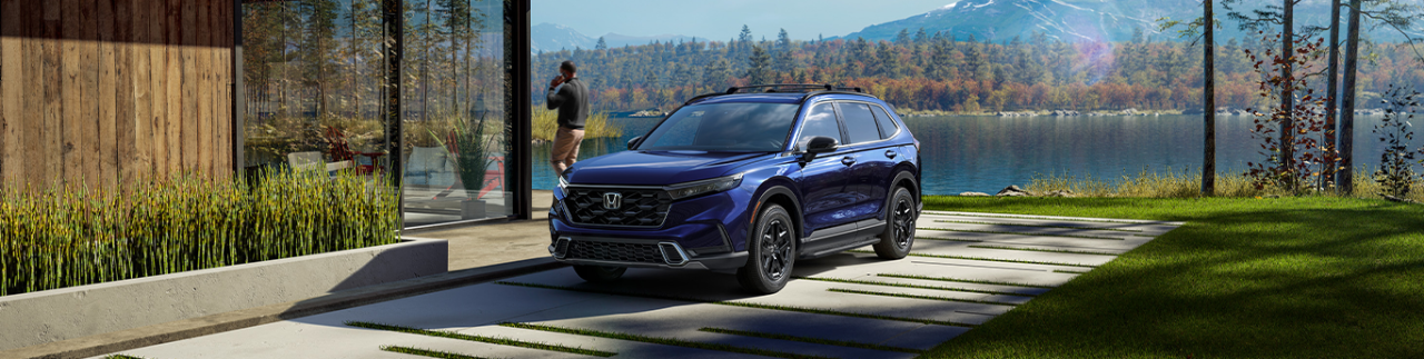 2024 Honda CR-V Hybrid at Washington Honda | Blue 2024 Honda CR-V parked outside on driveway near a lake 