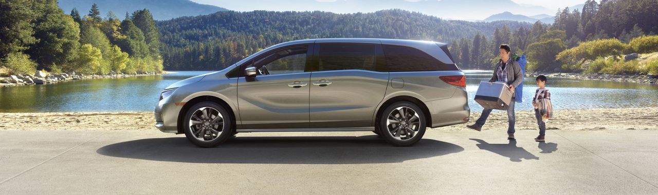 New 2025 Honda Odyssey at Delaney Honda | Side profile of a 2025 Honda Odyssey with dad and son loading up the trunk of the car