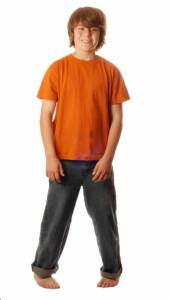 A young boy in an orange top is standing intoed or pigeon toed.