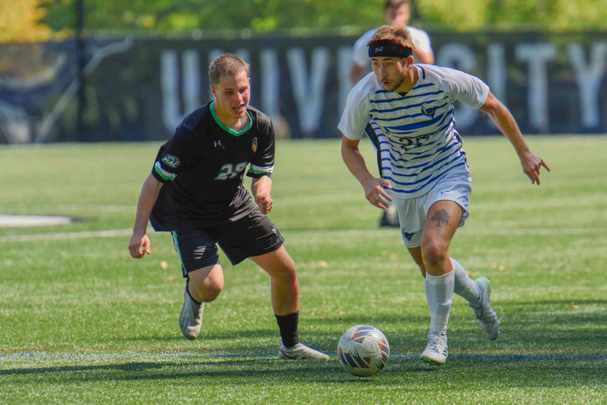 In an afternoon contest on Edith Robb Dixon field, Ethan Emery races up the field in Cabrini's home white jersey's with blue stripes as a Delaware Valley defender in black runs with him