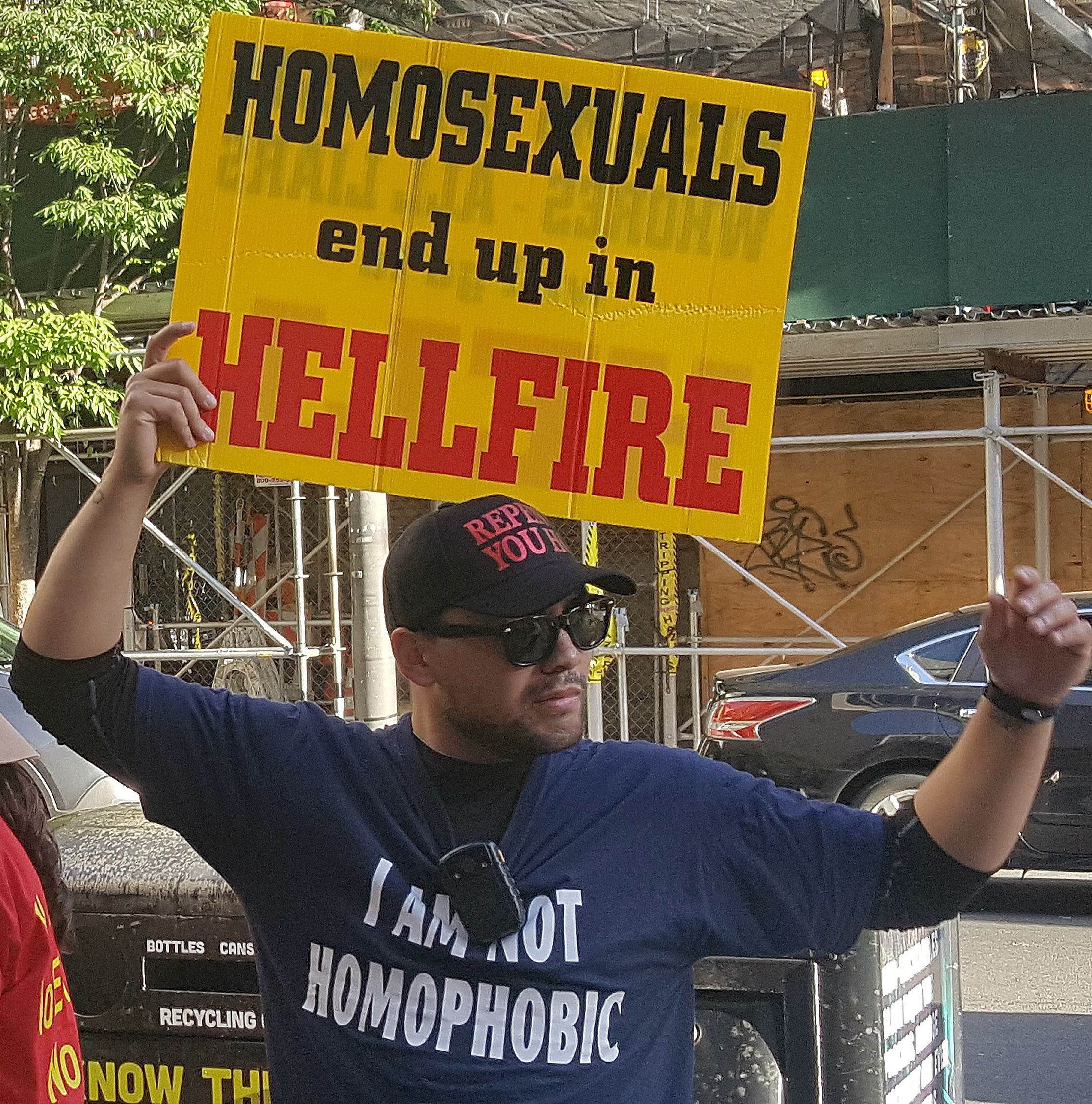 A protestor holds a sign that reads "Homosexuals end up in Hellfire."