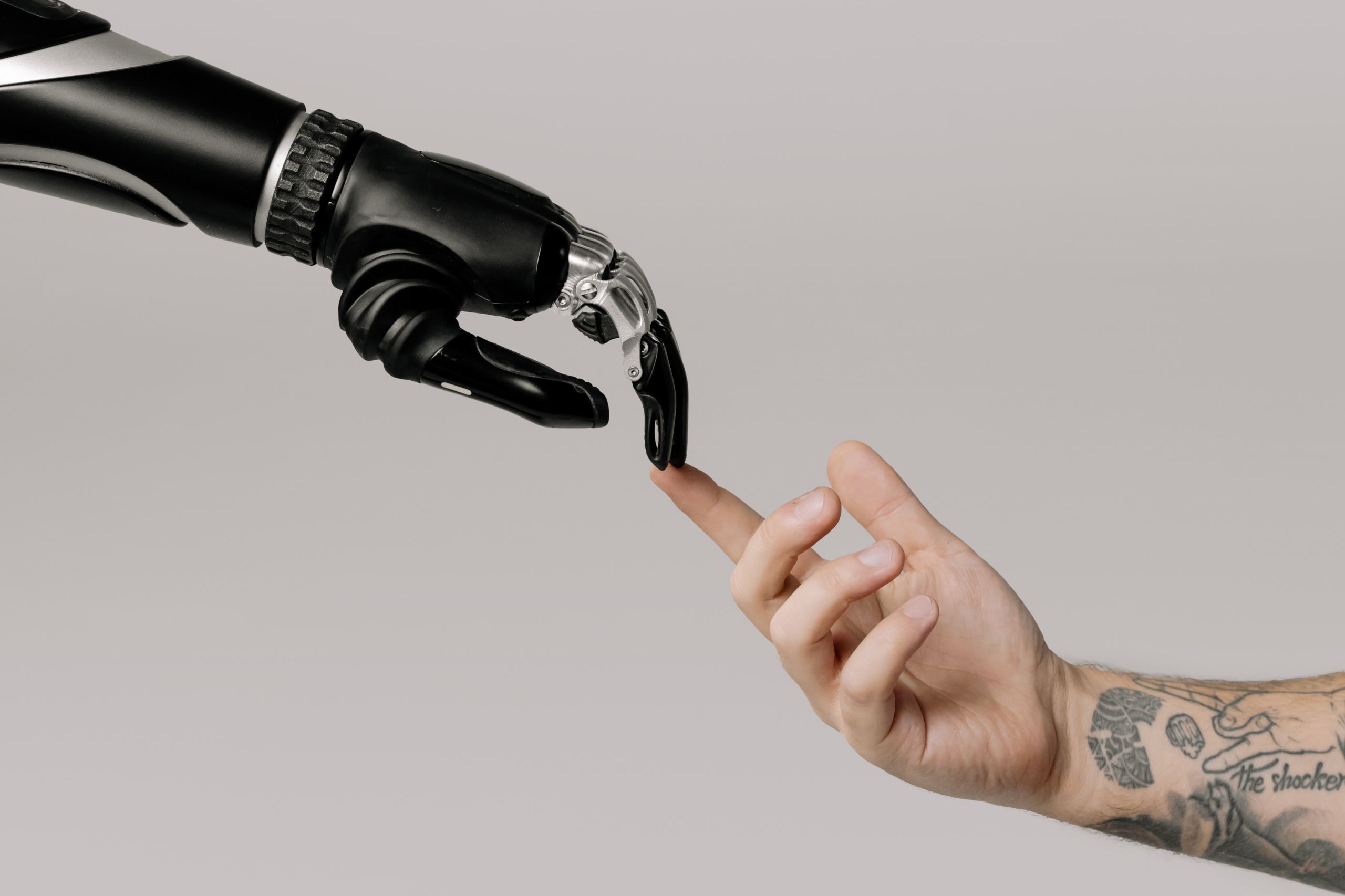 Photo of robot arm and human arm touching downloaded from pexels. The photo is by cottonbro studio