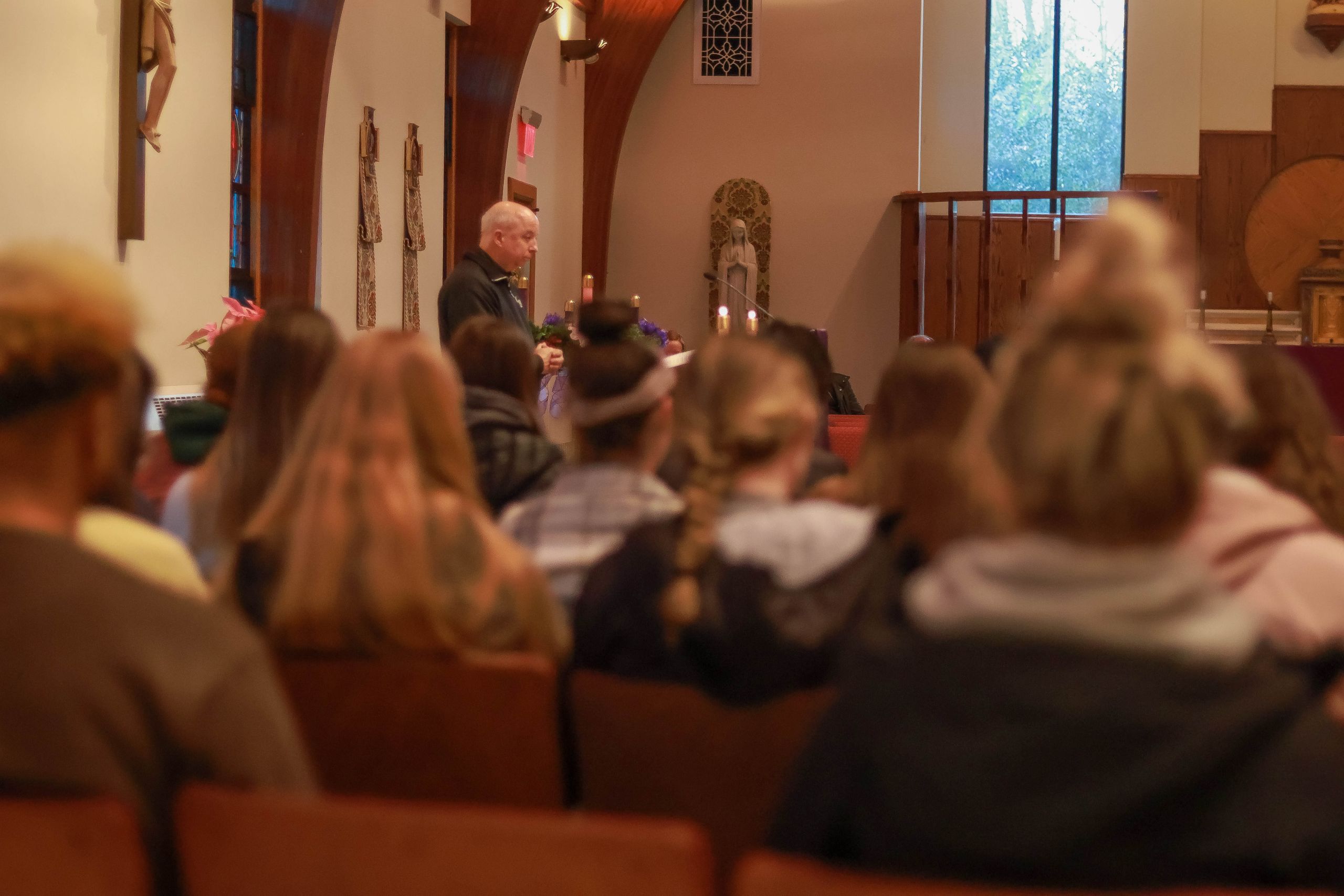 A priest leads a group of students in powerful prayer at prayer service in chapel 