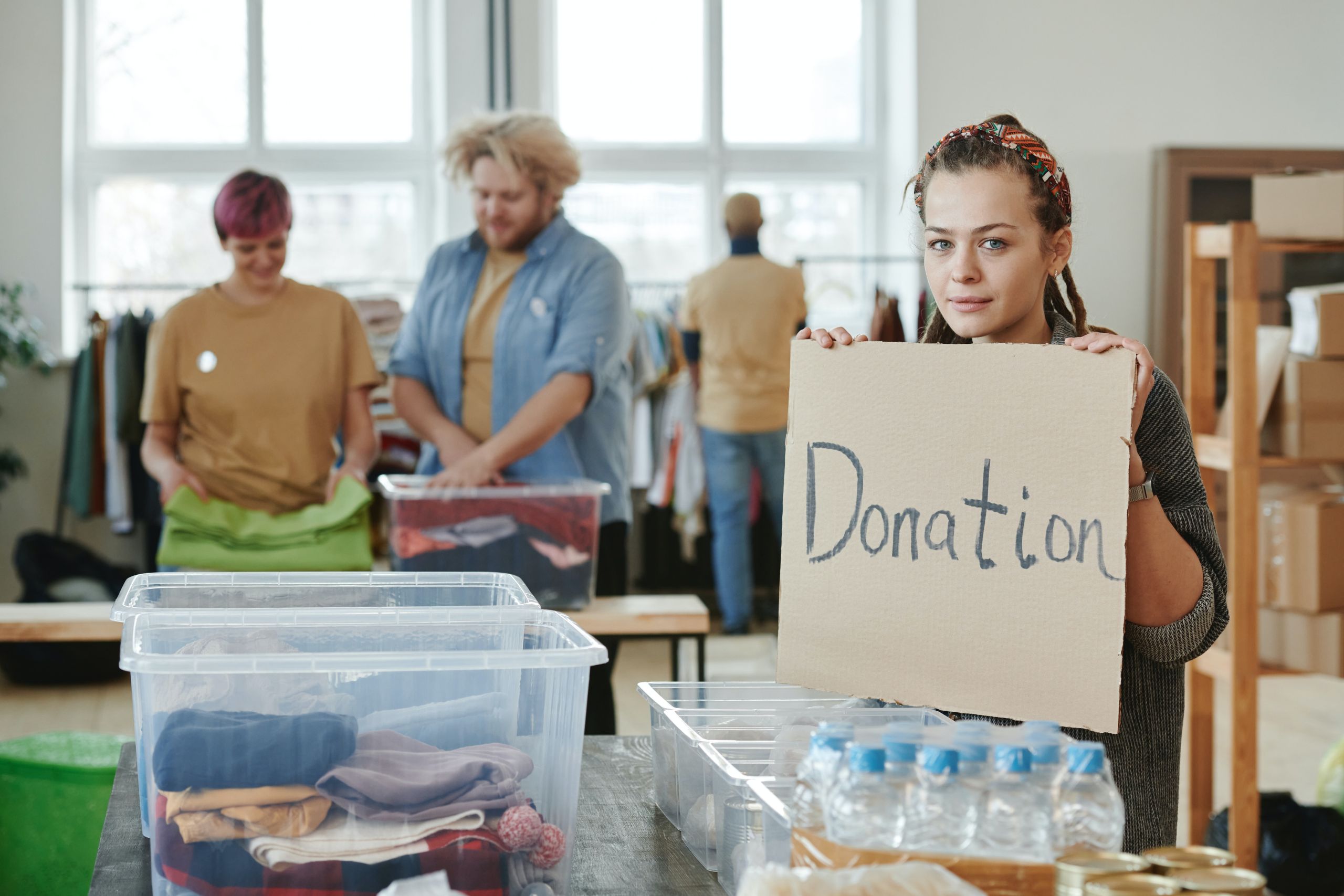 People packing goods into boxes at donation center. Photo by Julia M Cameron from Pexels.