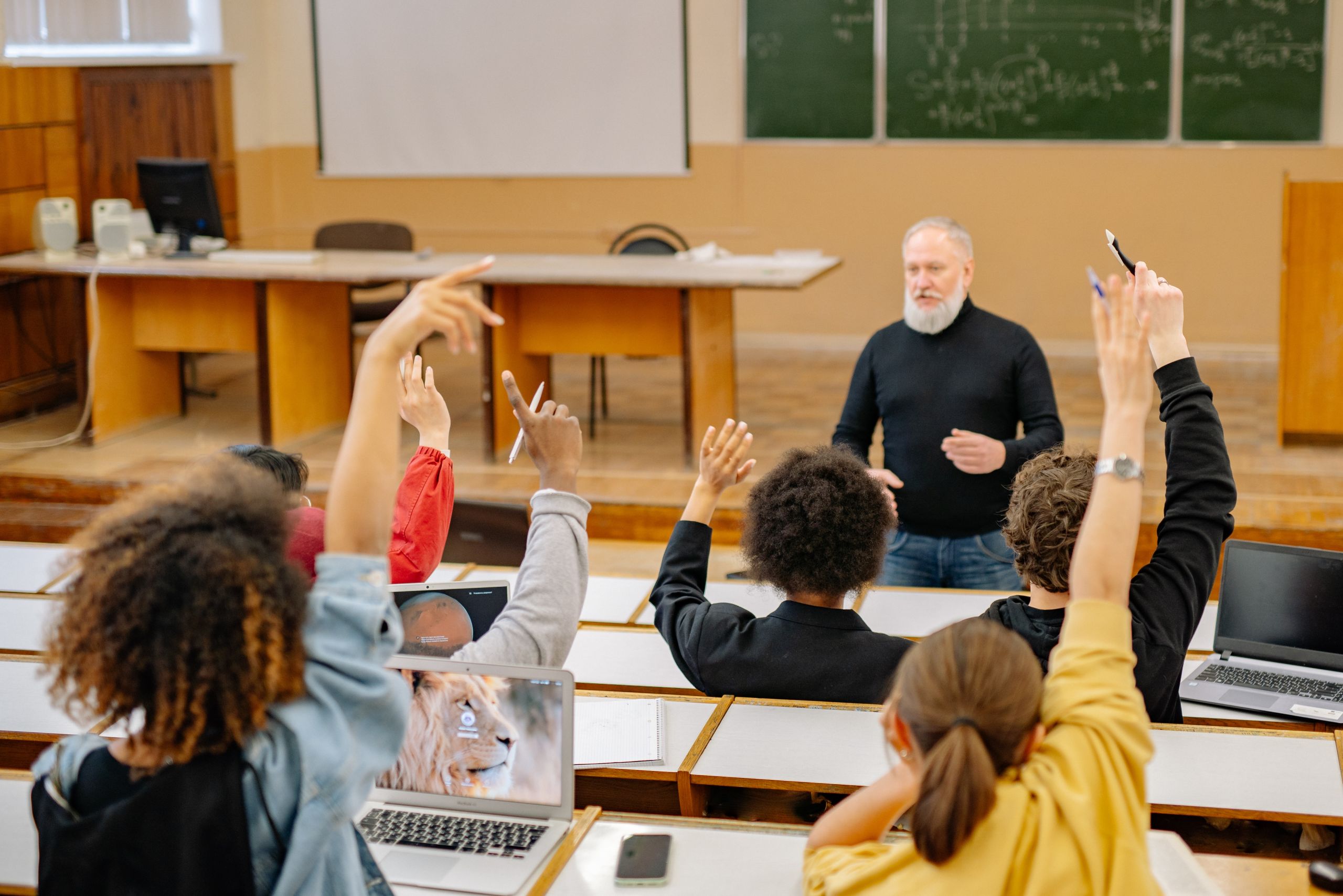Students raising their hands to speak in a lecture. Photo by Yan Krukau via Pexels.