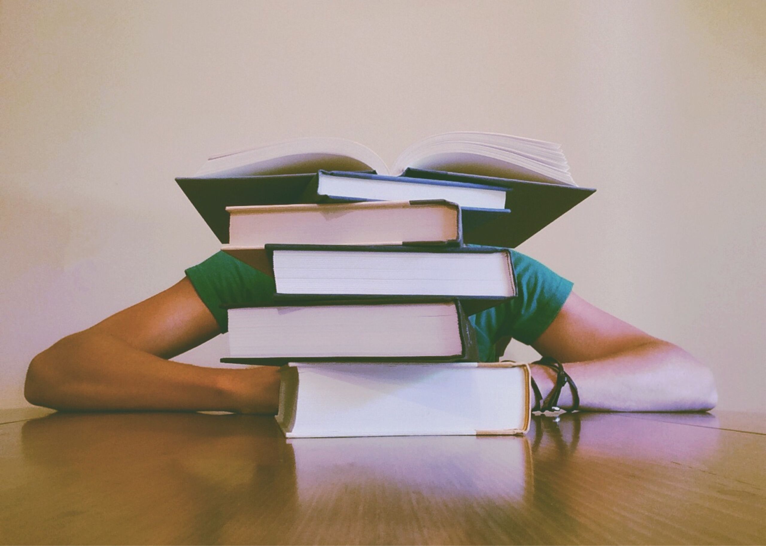 A student behind a stack of books with heavy workload. Photo by Pixabay from Pexels.