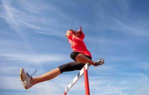 A woman hurdling with a blue sky background