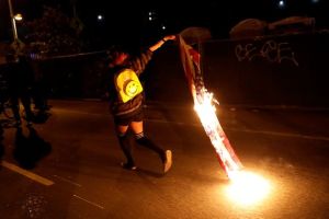 Photo by REUTERS. A demonstrator in Oakland, California runs while holding a burning flag.