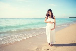 A pregnant lady walks along a beautiful beach