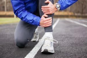 A man in running gear holds his shin
