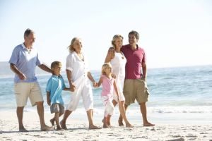 A family of three generations are walking together on a beach