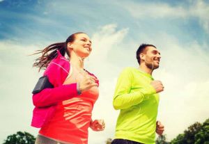 A man and a woman are running in bright clothes with earplugs in