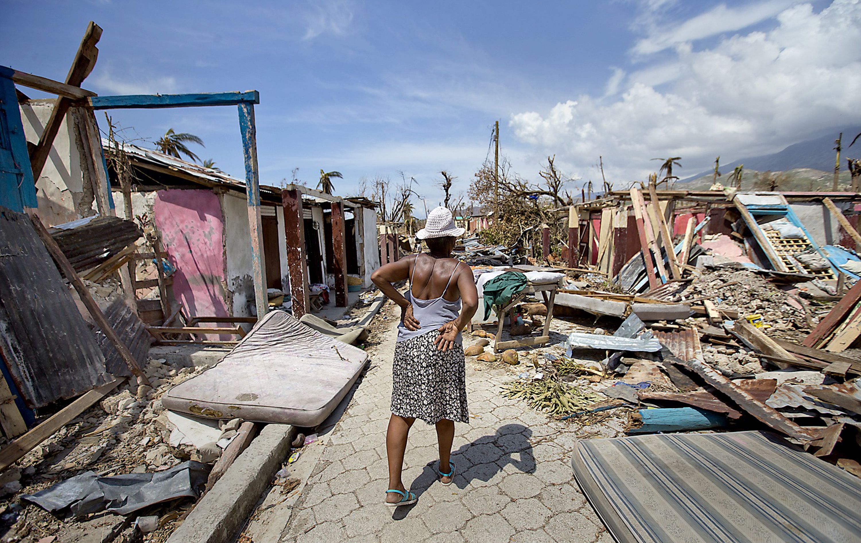 An elderly woman walks along a debris filled street in Roche a Bateau, Haiti on Sunday, Oct. 9, 2016. (Patrick Farrell/Miami Herald/TNS)