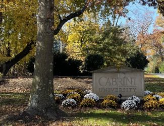 Cabrini University entrance sign with flower bed and trees