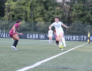 A Cabrini women's soccer in their home white uniforms player dribbles the ball up the sideline of Edith Robb Dixon field in a non-conference matchup against Eastern University