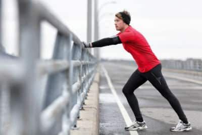 A man stretches his calf muscles on a bridge to prevent heel pain.