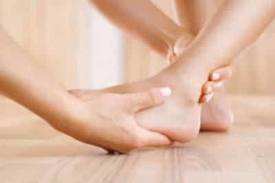 A podiatrist's hands are palpating an ankle and foot.