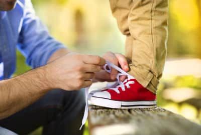 A Dad is tying his sons shoes