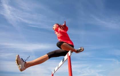 A woman hurdling with a blue sky background