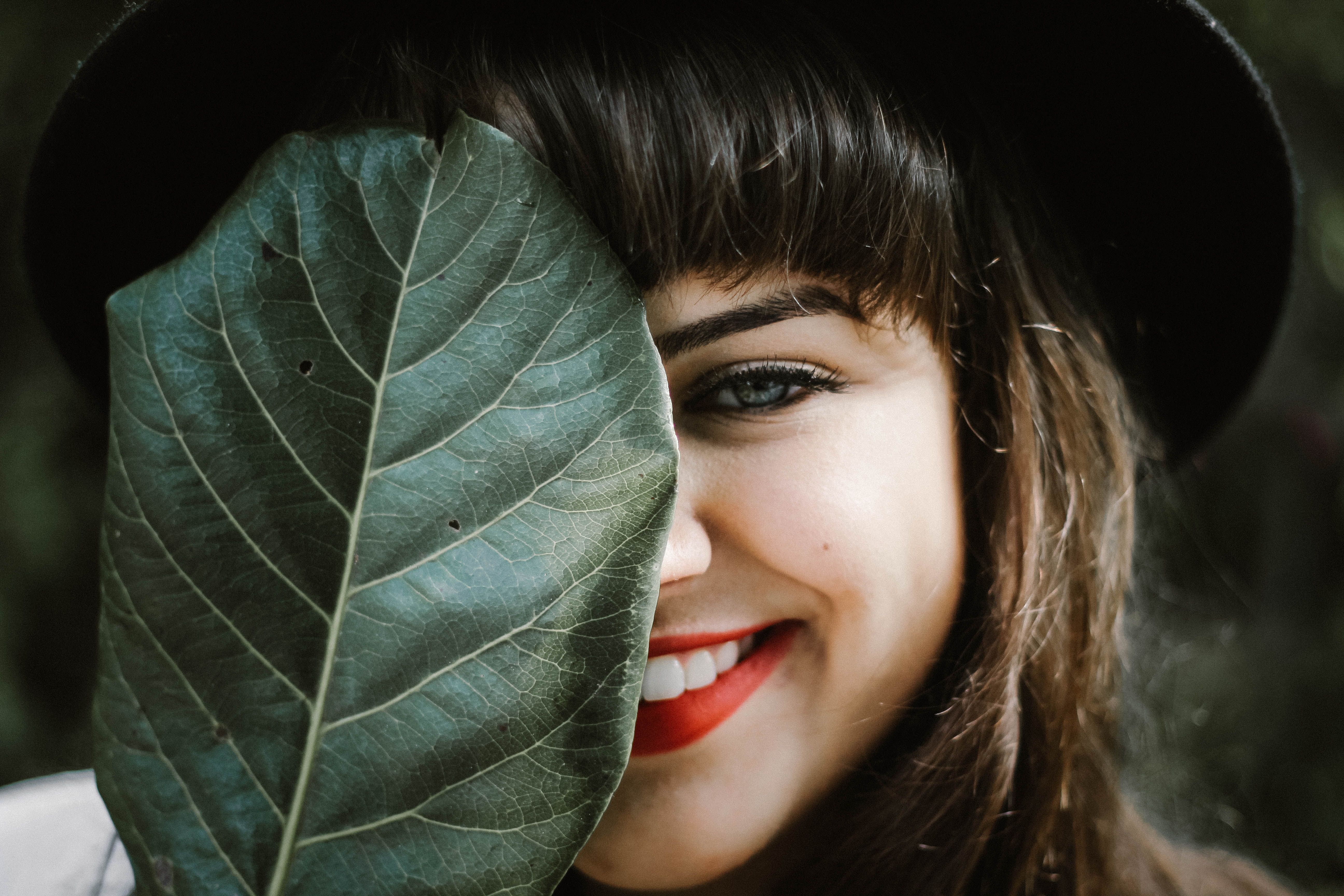 Fresh Hair with NATULIQUE girl with bangs holding a leaf and smiling