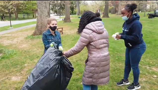 Three Cabrini students in clats with Trash bags collecting trash from the open space on campus