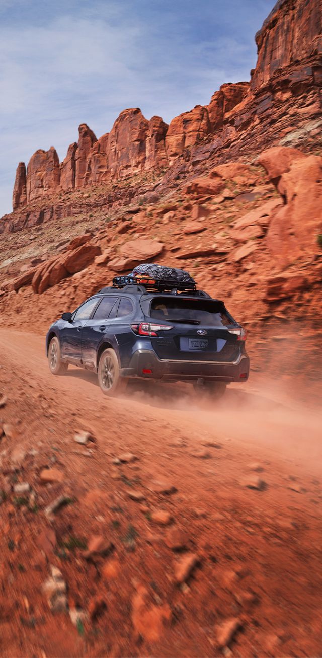 2025 Subaru Outback at Delaney Subaru in Indiana, PA | 2025 Subaru Outback driving up a rocky hill with cargo on the roof
