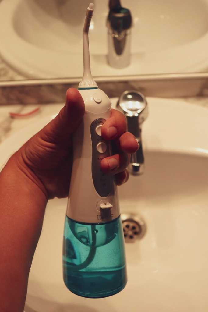 El mejor irrigador dental - Comparativa 2020 25 iTeknic en la mano encima de un lavabo