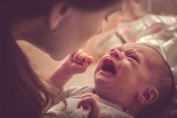 Ο Λευκός Πύργος της Θεσσαλονίκης, ένα κυλινδρικό πέτρινο κτίσμα με πολεμίστρες στην κορυφή και μικρά παράθυρα, δεσπόζει κάτω από έναν γαλανό ουρανό με διάσπαρτα σύννεφα. Μια ελληνική σημαία κυματίζει στην κορυφή του πύργου. Πράσινα δέντρα και θάμνοι βρίσκονται στη βάση του πύργου, ενώ κτίρια διαμερισμάτων φαίνονται στο κάτω δεξί μέρος της εικόνας.