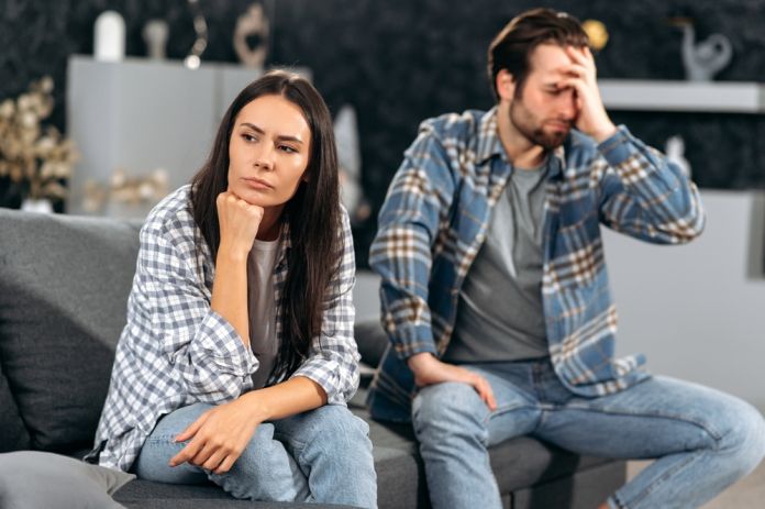Μια φωτογραφία μιας γυναίκας που στέκεται δίπλα σε ένα αγόρι που κάθεται σε ένα θρανίο. Η γυναίκα κρατάει το χέρι της στον ώμο του αγοριού, ενώ το αγόρι γράφει με μολύβι σε ένα τετράδιο και κοιτάζει προς το μέρος της. Το σκηνικό μοιάζει με σχολική τάξη.